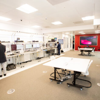 The SONIC Labs facilities. A line of computers on the left hand side leading to a server room. On the right are large tables for collaborative working