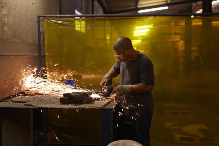 Steel worker cutting steel items at factory