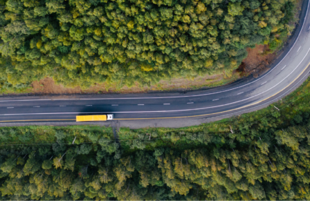 Yellow haulage vehicle drives solitary through a forest